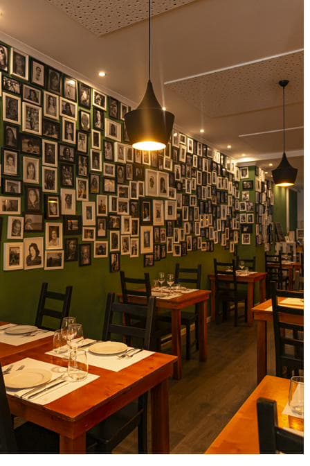 Parede verde do Mãe Restaurante coberta de fotografias emolduradas de mães e avós dos clientes